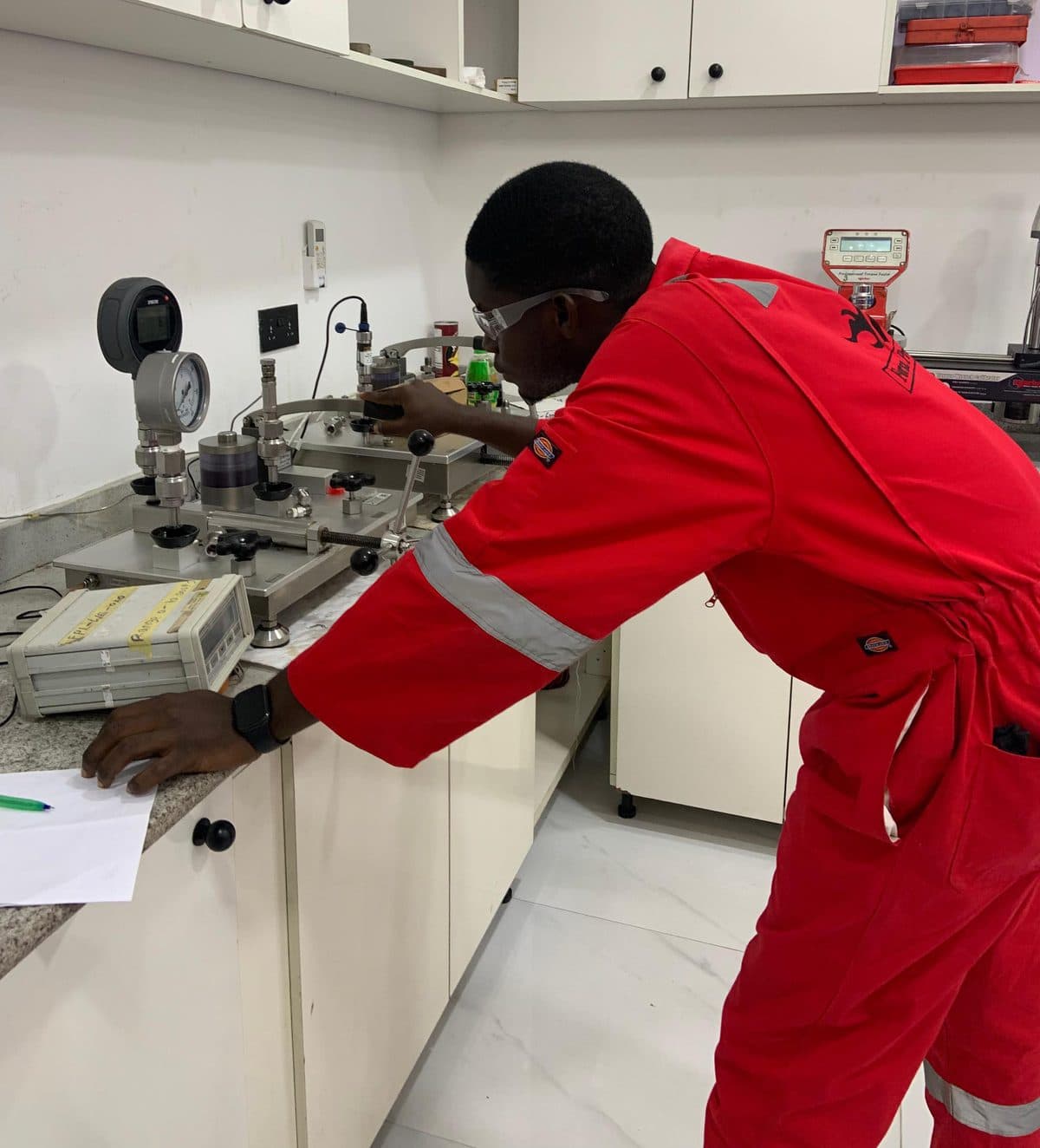 Forza Projects technician in PPE calibrating pressure gauges and instruments on a laboratory bench